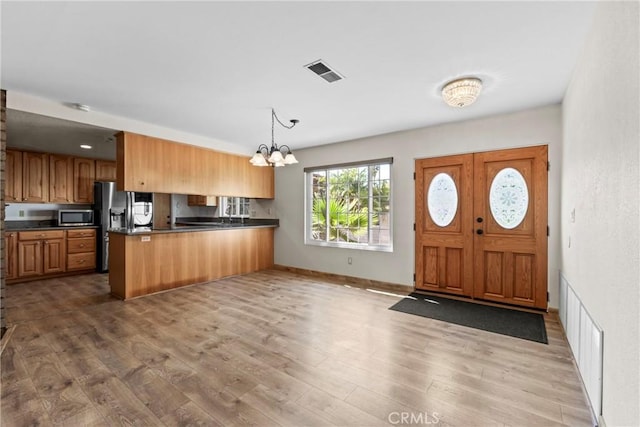 8609 Dunwoodie Rd, Santee, CA 92071 - kitchen featuring appliances with stainless steel finishes, dark countertops, a peninsula, a chandelier, and wood finished floors