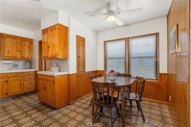 4840 Heleo Ave, Temple City, CA 91780 - kitchen featuring a wainscoted wall, brown cabinets, ceiling fan, wooden walls, and decorative backsplash