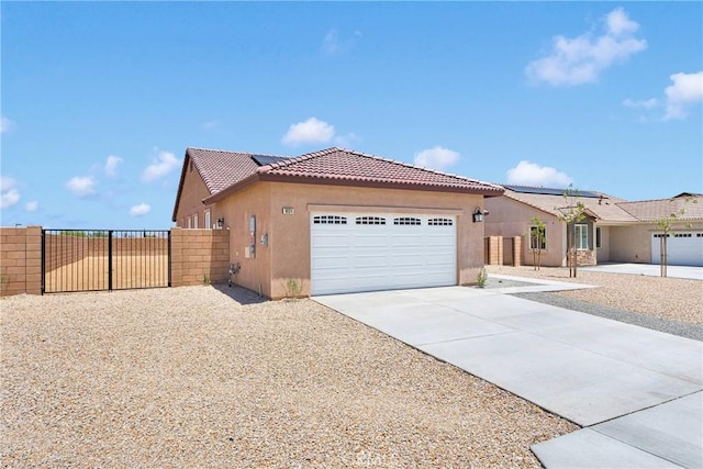 16124 Pablo Ct, Victorville, CA 92395 - view of front facade featuring stucco siding, concrete driveway, an attached garage, a tile roof, and solar panels