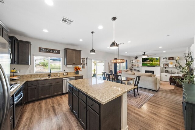 24212 Bay Laurel Ave, Murrieta, CA 92562 - kitchen featuring appliances with stainless steel finishes, wood finished floors, a center island, recessed lighting, and light stone counters
