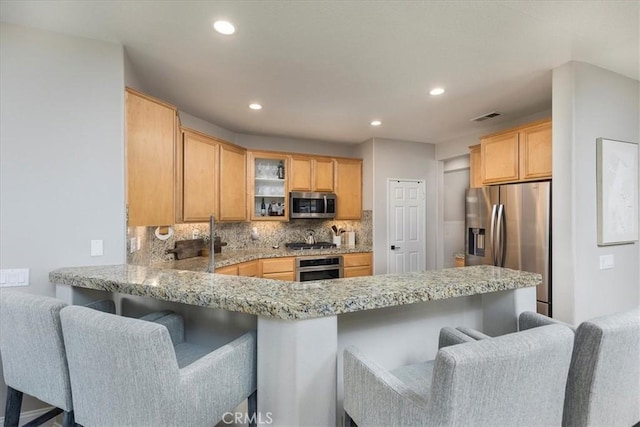 32669 Armoise Dr, Winchester, CA 92596 - kitchen with stainless steel appliances, a peninsula, glass insert cabinets, decorative backsplash, and a breakfast bar area