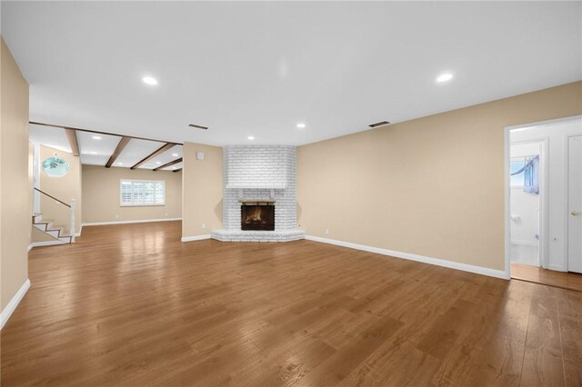 4159 Redline Dr, Lakewood, CA 90713 - unfurnished living room with wood finished floors, a brick fireplace, stairs, and recessed lighting