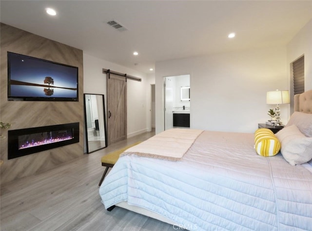 5435 W 76th St, Los Angeles, CA 90045 - bedroom featuring a barn door, light wood-type flooring, recessed lighting, a large fireplace, and ensuite bathroom