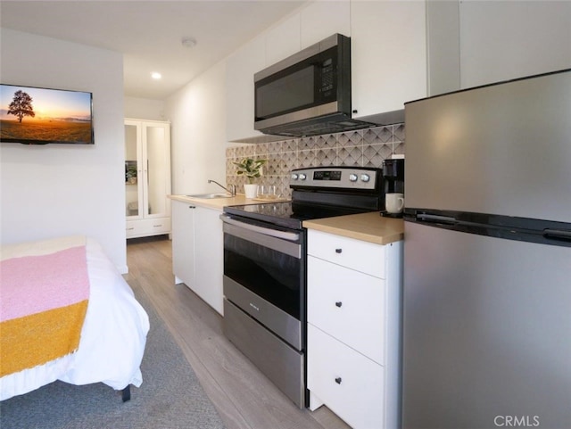 5435 W 76th St, Los Angeles, CA 90045 - kitchen with stainless steel appliances, light wood-type flooring, light countertops, white cabinets, and decorative backsplash
