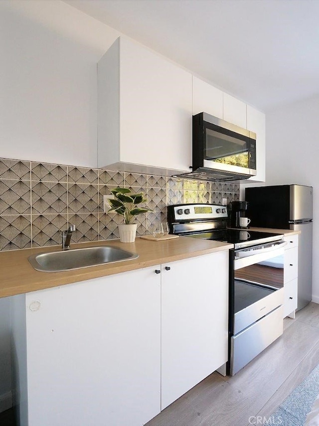 5435 W 76th St, Los Angeles, CA 90045 - kitchen featuring appliances with stainless steel finishes, white cabinets, decorative backsplash, light wood-style flooring, and light countertops