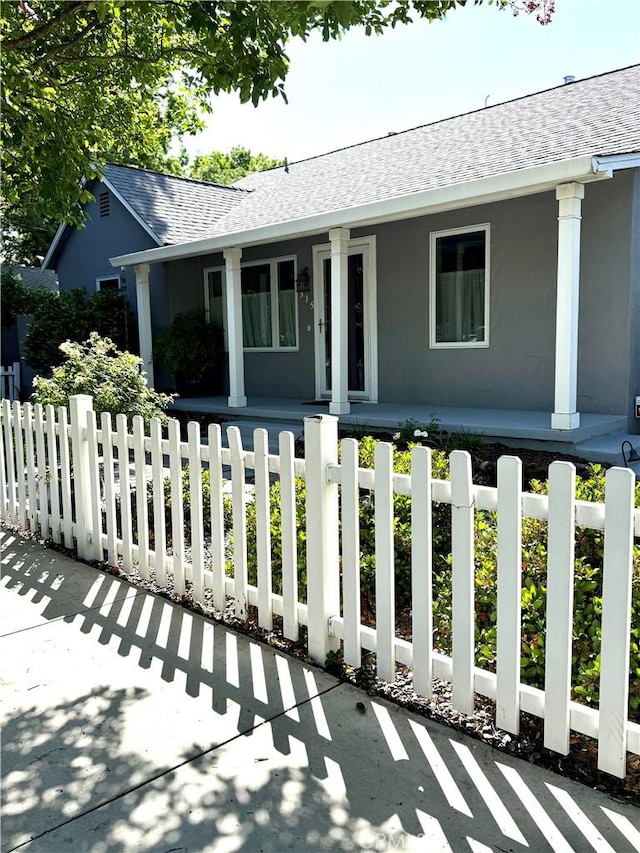 315 W 6th Ave, Chico, CA 95926 - ranch-style house featuring a porch, roof with shingles, a fenced front yard, and stucco siding