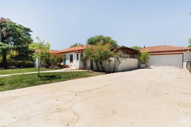 700 Hillcrest Dr, Bakersfield, CA 93305 - mediterranean / spanish house with a tiled roof, stucco siding, concrete driveway, a front lawn, and a garage