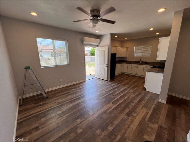 246 E 27th St, San Bernardino, CA 92404 - kitchen featuring dark countertops, a wall mounted air conditioner, white cabinets, freestanding refrigerator, and a ceiling fan