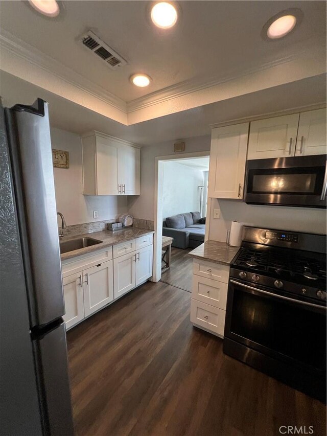 246 E 27th St, San Bernardino, CA 92404 - kitchen with freestanding refrigerator, black gas range, ornamental molding, white cabinets, and a tray ceiling