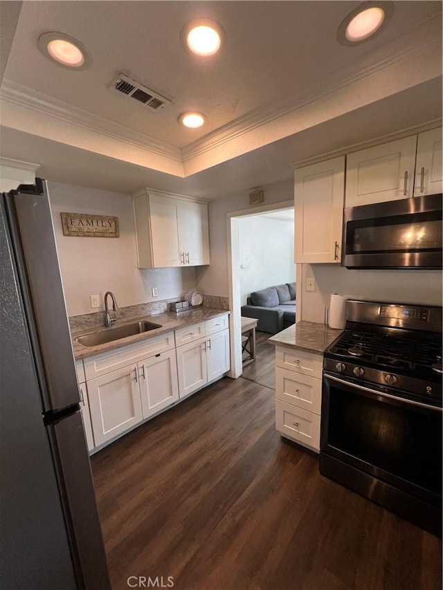 246 E 27th St, San Bernardino, CA 92404 - kitchen with appliances with stainless steel finishes, a raised ceiling, crown molding, white cabinetry, and dark wood-style flooring