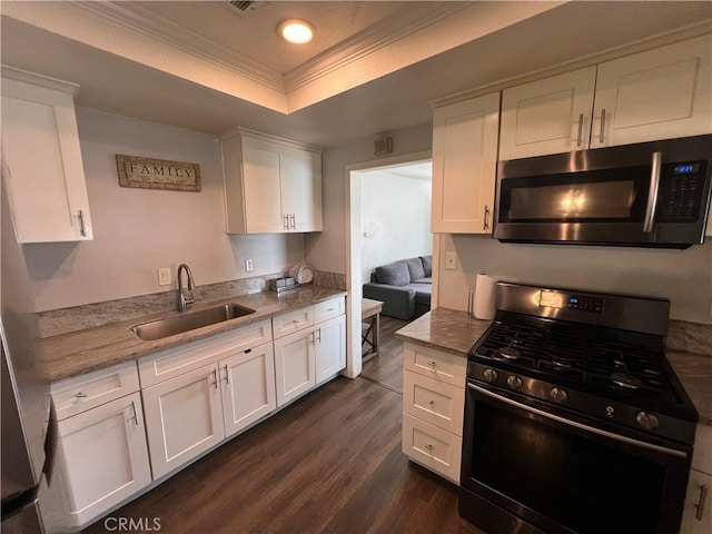246 E 27th St, San Bernardino, CA 92404 - kitchen with gas range oven, stainless steel microwave, a raised ceiling, white cabinets, and ornamental molding