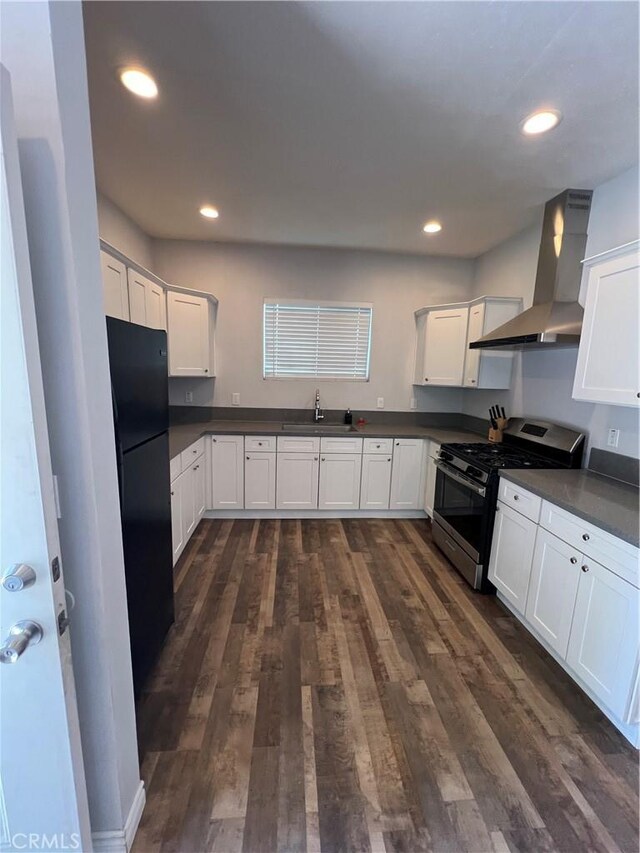 246 E 27th St, San Bernardino, CA 92404 - kitchen with stainless steel range with gas cooktop, wall chimney exhaust hood, freestanding refrigerator, dark countertops, and dark wood-type flooring