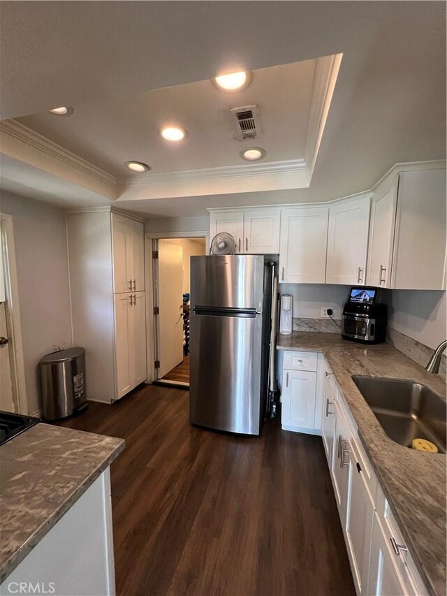 246 E 27th St, San Bernardino, CA 92404 - kitchen featuring freestanding refrigerator, a tray ceiling, ornamental molding, dark wood-type flooring, and white cabinetry