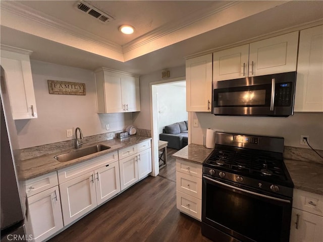 246 E 27th St, San Bernardino, CA 92404 - kitchen featuring black gas range oven, stainless steel microwave, white cabinets, dark wood finished floors, and a raised ceiling
