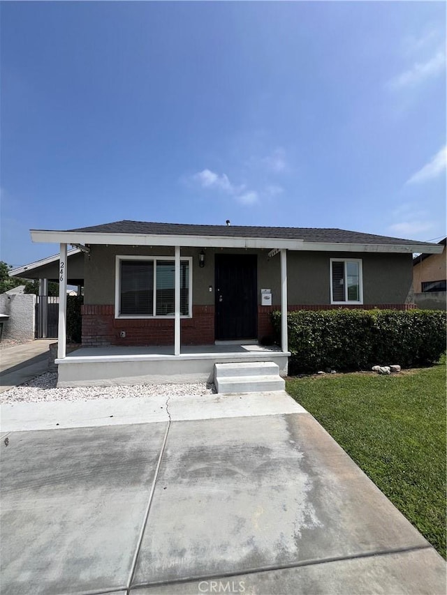 246 E 27th St, San Bernardino, CA 92404 - ranch-style home featuring brick siding, a porch, a front lawn, and roof with shingles