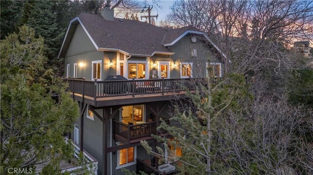 813 Brentwood Dr, Lake Arrowhead, CA 92352 - back of property at dusk with a shingled roof, a wooden deck, and a chimney