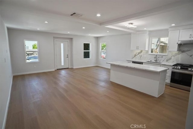 10324 Silverton Ave, Tujunga, CA 91042 - kitchen with gas range, under cabinet range hood, a kitchen island, decorative backsplash, and recessed lighting