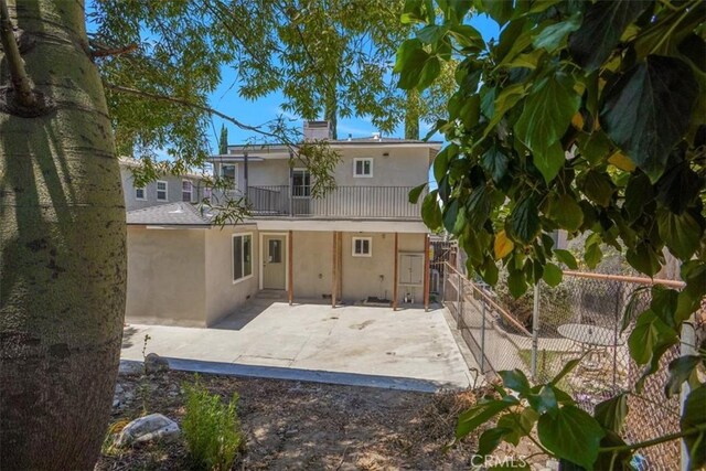10324 Silverton Ave, Tujunga, CA 91042 - rear view of house with stucco siding, a balcony, a fenced backyard, a patio, and a chimney