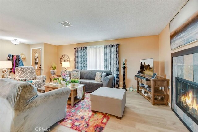 21821 Carlisle Rd, Apple Valley, CA 92307 - living room featuring a tiled fireplace, light wood-type flooring, and a textured ceiling