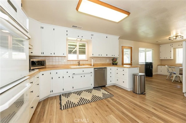 1019 W Monterey St, Orland, CA 95963 - kitchen with stainless steel appliances, light wood-type flooring, a peninsula, tasteful backsplash, and light countertops