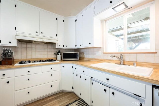 1019 W Monterey St, Orland, CA 95963 - kitchen with stainless steel microwave, under cabinet range hood, decorative backsplash, white gas cooktop, and light countertops