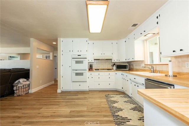 1019 W Monterey St, Orland, CA 95963 - kitchen featuring stainless steel appliances, light countertops, white cabinets, light wood-style flooring, and backsplash