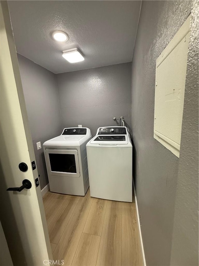 1804 Ewing Ct, Hacienda Heights, CA 91745 - washroom with washing machine and dryer, a textured wall, a textured ceiling, light wood finished floors, and electric panel