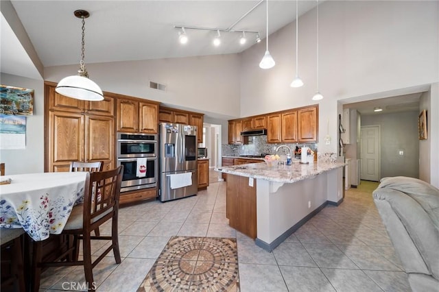 11056 Orchard View Ln, Riverside, CA 92503 - kitchen featuring appliances with stainless steel finishes, a peninsula, a breakfast bar, brown cabinetry, and decorative light fixtures