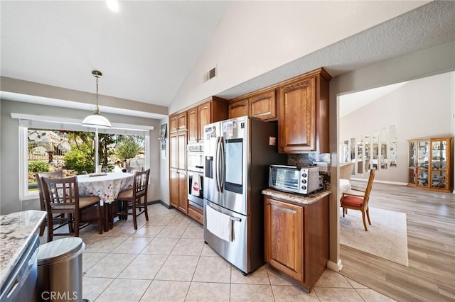11056 Orchard View Ln, Riverside, CA 92503 - kitchen with appliances with stainless steel finishes, brown cabinetry, pendant lighting, light stone counters, and high vaulted ceiling