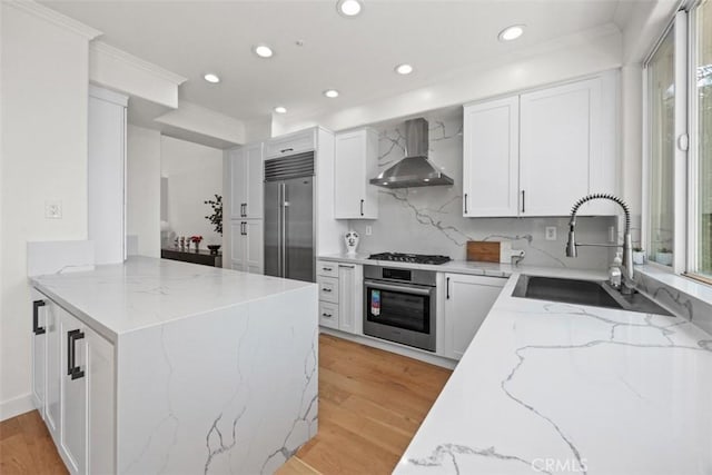 1872 Caminito De La Narcissa, Glendale, CA 91208 - kitchen with appliances with stainless steel finishes, wall chimney range hood, a peninsula, light wood-type flooring, and recessed lighting