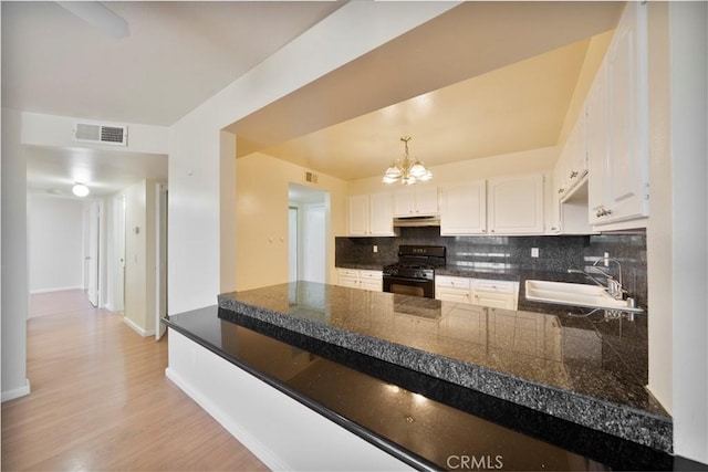 981 S St Andrews Pl Unit 104, Los Angeles, CA 90019 - kitchen with black gas range oven, tasteful backsplash, a chandelier, under cabinet range hood, and a peninsula