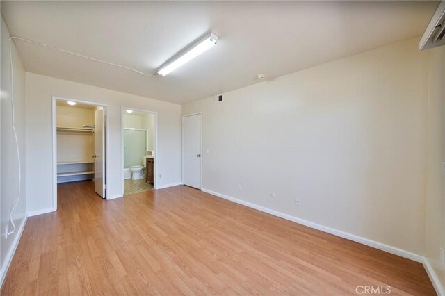 981 S St Andrews Pl Unit 104, Los Angeles, CA 90019 - unfurnished bedroom with a spacious closet, light wood-style flooring, a closet, and ensuite bath
