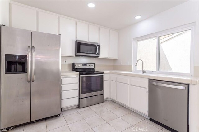 19533 Rinaldi St Unit 48, Porter Ranch, CA 91326 - kitchen with appliances with stainless steel finishes, white cabinets, tile countertops, recessed lighting, and light tile patterned floors