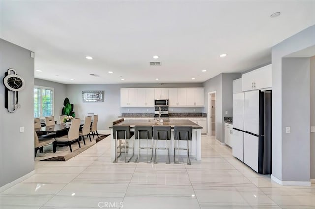 18348 Cachet Way, Canyon Country, CA 91350 - kitchen with freestanding refrigerator, stainless steel microwave, a breakfast bar area, white cabinetry, and recessed lighting