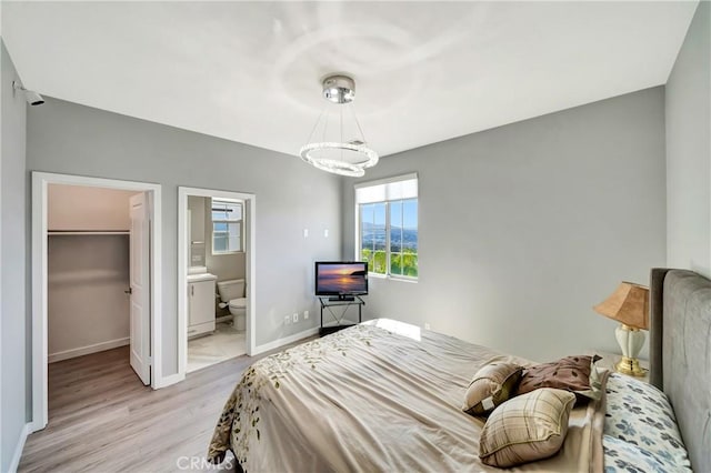 18348 Cachet Way, Canyon Country, CA 91350 - bedroom with light wood finished floors, a chandelier, a walk in closet, connected bathroom, and a closet