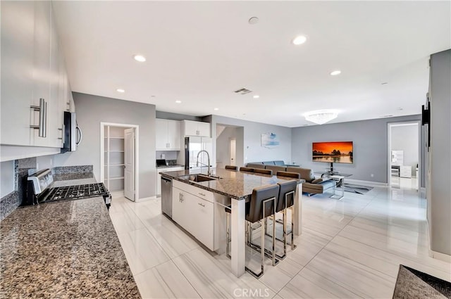 18348 Cachet Way, Canyon Country, CA 91350 - kitchen featuring stainless steel appliances, dark stone counters, a kitchen island with sink, open floor plan, and white cabinets