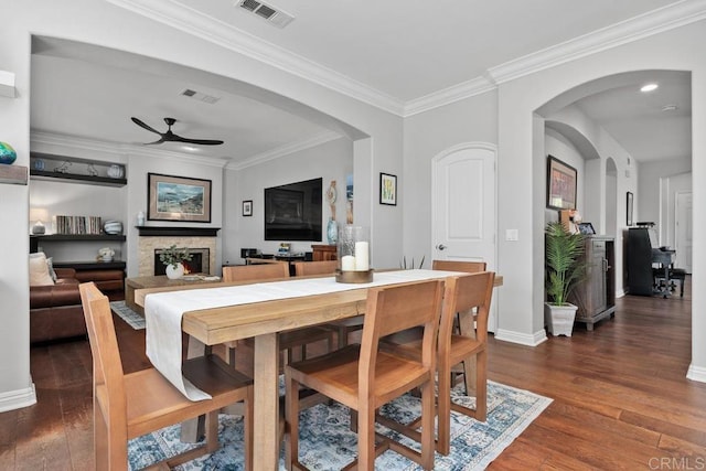 923 Citrine Way, San Marcos, CA 92078 - dining room featuring a ceiling fan, wood finished floors, a fireplace, crown molding, and arched walkways