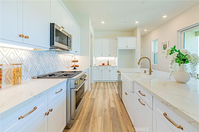 27505 Illumination Ct, Valencia, CA 91381 - kitchen featuring stainless steel appliances, light wood-style flooring, white cabinets, light stone countertops, and recessed lighting