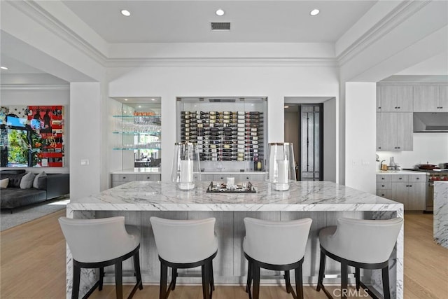 16 Seawatch, Newport Coast, CA 92657 - kitchen with extractor fan, a kitchen bar, light wood-style flooring, a large island, and high end stove