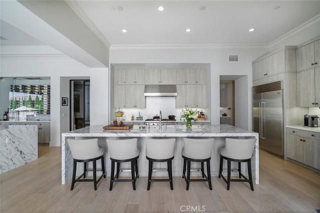 16 Seawatch, Newport Coast, CA 92657 - kitchen featuring stainless steel built in refrigerator, under cabinet range hood, a kitchen breakfast bar, crown molding, and light stone counters