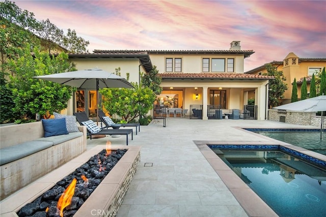 16 Seawatch, Newport Coast, CA 92657 - rear view of house featuring stucco siding, an outdoor living space with a fire pit, a chimney, an outdoor pool, and a patio