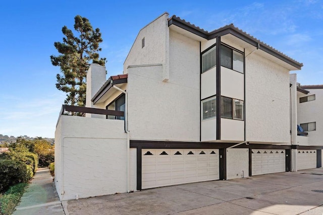 7528 Jerez Ct Unit 6, Carlsbad, CA 92009 - view of property exterior with stucco siding, an attached garage, driveway, and a chimney
