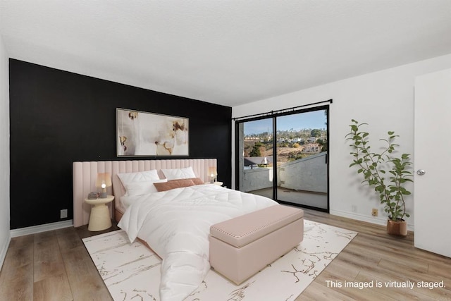 7528 Jerez Ct Unit 6, Carlsbad, CA 92009 - bedroom featuring access to outside, an accent wall, and wood finished floors