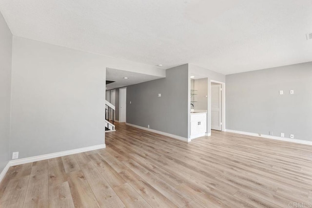 7528 Jerez Ct Unit 6, Carlsbad, CA 92009 - unfurnished living room featuring stairs and light wood-style flooring