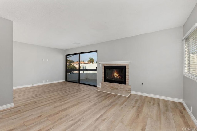 7528 Jerez Ct Unit 6, Carlsbad, CA 92009 - unfurnished living room featuring light wood-type flooring and a tiled fireplace