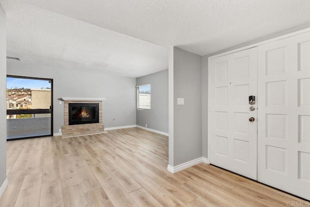 7528 Jerez Ct Unit 6, Carlsbad, CA 92009 - entrance foyer featuring a textured ceiling, light wood finished floors, and a glass covered fireplace