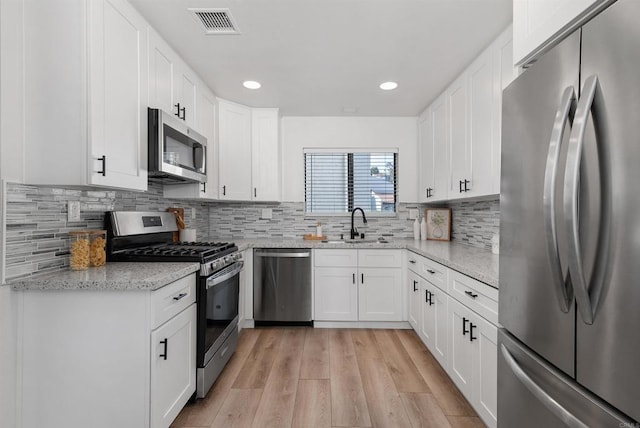 7528 Jerez Ct Unit 6, Carlsbad, CA 92009 - kitchen featuring appliances with stainless steel finishes, light wood-type flooring, recessed lighting, light stone countertops, and white cabinetry