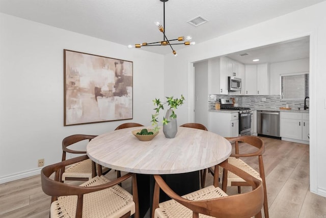 7528 Jerez Ct Unit 6, Carlsbad, CA 92009 - dining room with a chandelier and light wood-style flooring