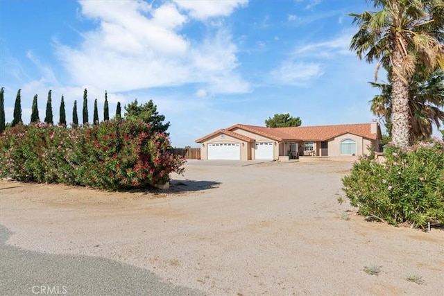 14296 Bieri St, Mojave, CA 93501 - view of front facade with an attached garage, dirt driveway, and stucco siding
