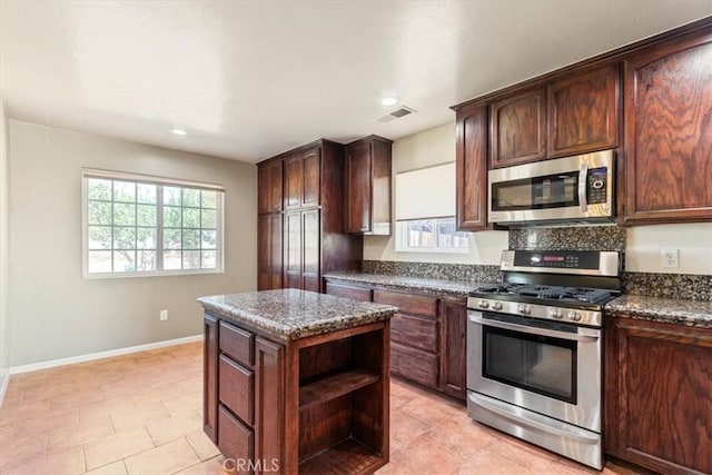 14296 Bieri St, Mojave, CA 93501 - kitchen with stainless steel appliances, open shelves, a center island, dark stone countertops, and dark brown cabinetry